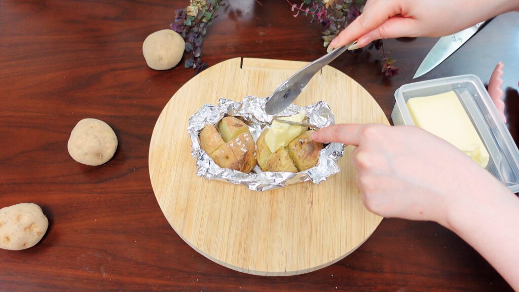 place a generous amount of butter into the incisions of the potatoes