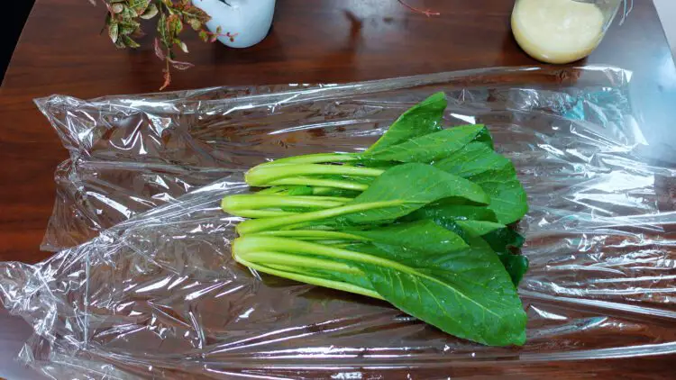 wash the leaf vegetable of your choice and then place it on the plastic wrap