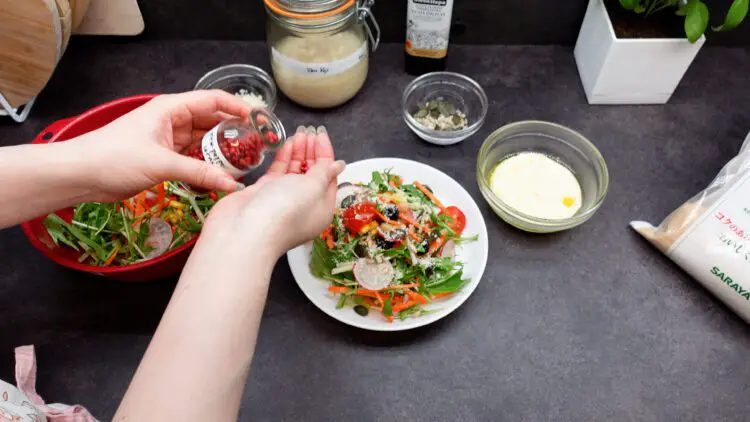sprinkle some seeds, Parmigiano Reggiano, and pink peppercorns over the salad