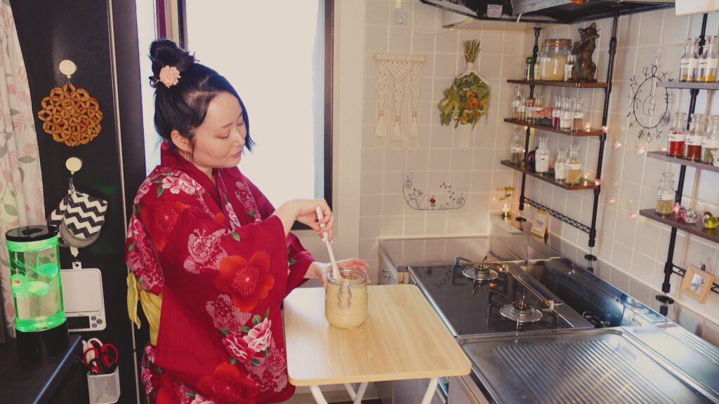 sakura yubi in kitchen stirring shio koji in a jar