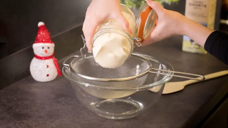 emptying a jar of kefir into a strainer over a bowl