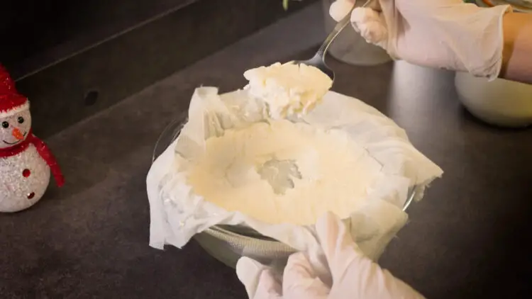 scooping kefir cheese with a spoon from a cloth