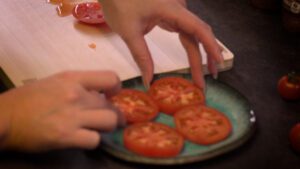 placing tomato slices on a plate