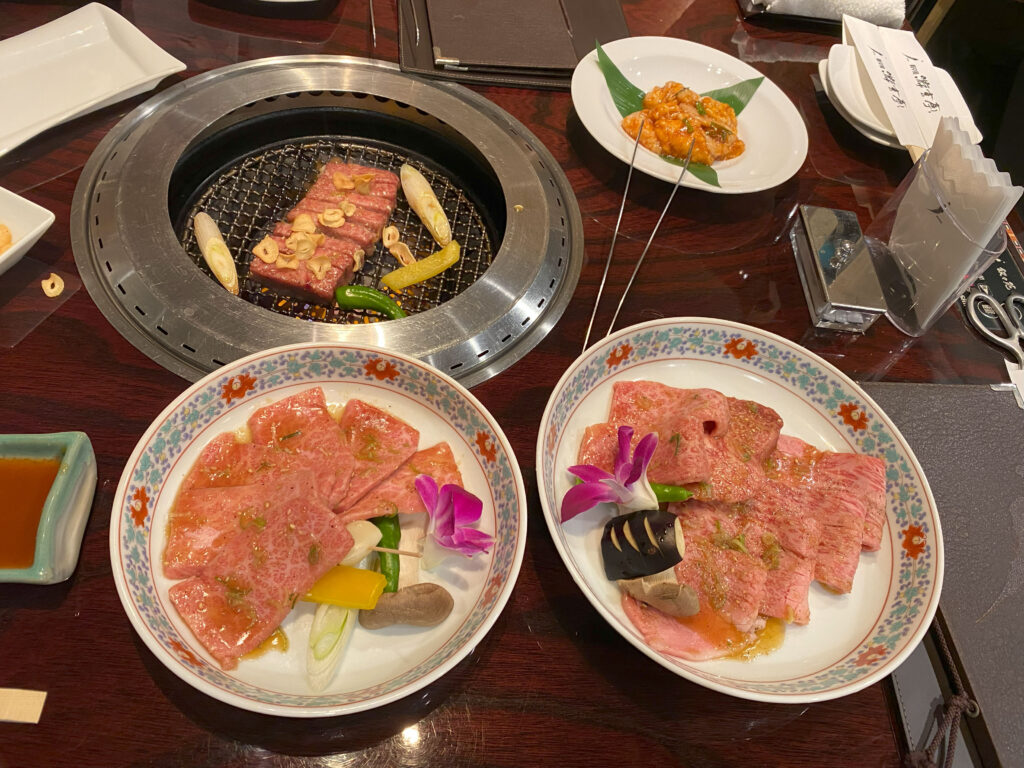plates of sliced meat served around the grill in Yugentei Shinjuku