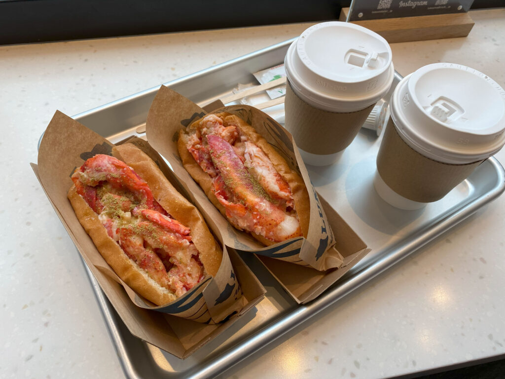 two lobster rolls and two coffee on a tray